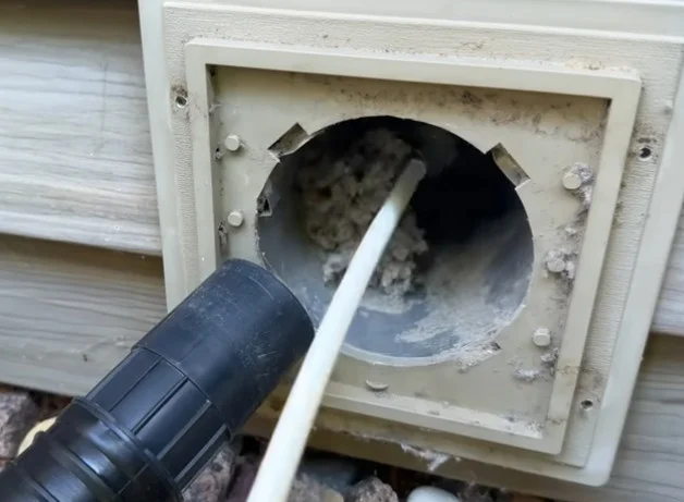 Rotary brush clearing a clogged dryer vent hood on a St. Augustine, FL home